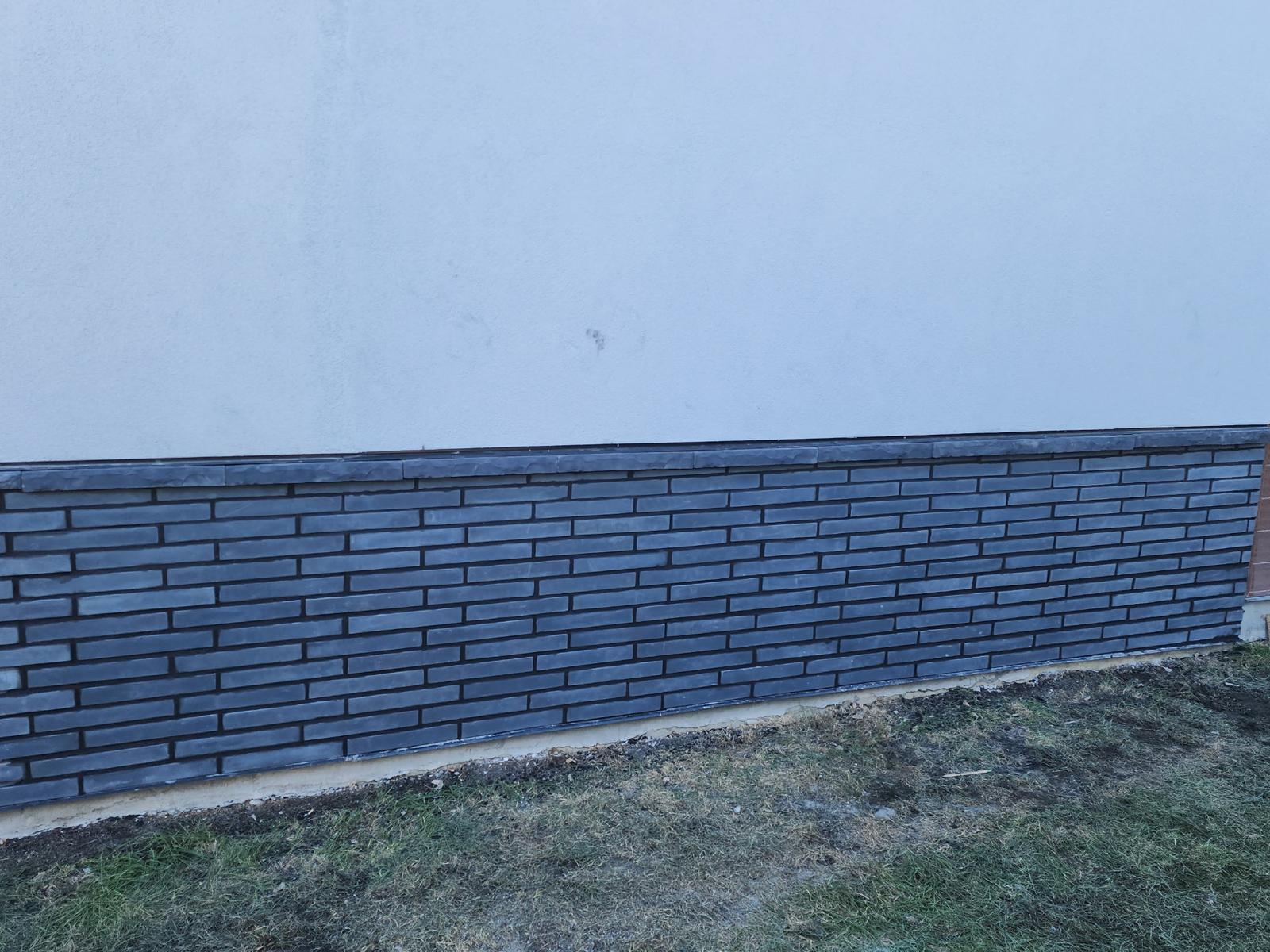 The same wall after a smooth stucco re-coat with dark brick veneer and cap stone along the base