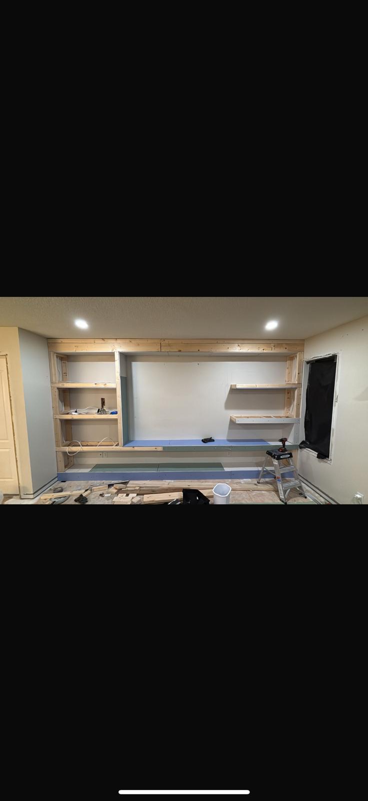 Custom built-in shelving and media wall framed in a basement